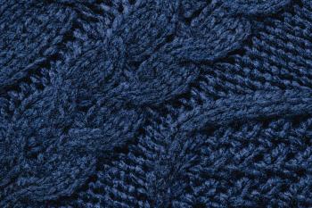 A dark blue piece of knitted fabric with an intricate cabled pattern.